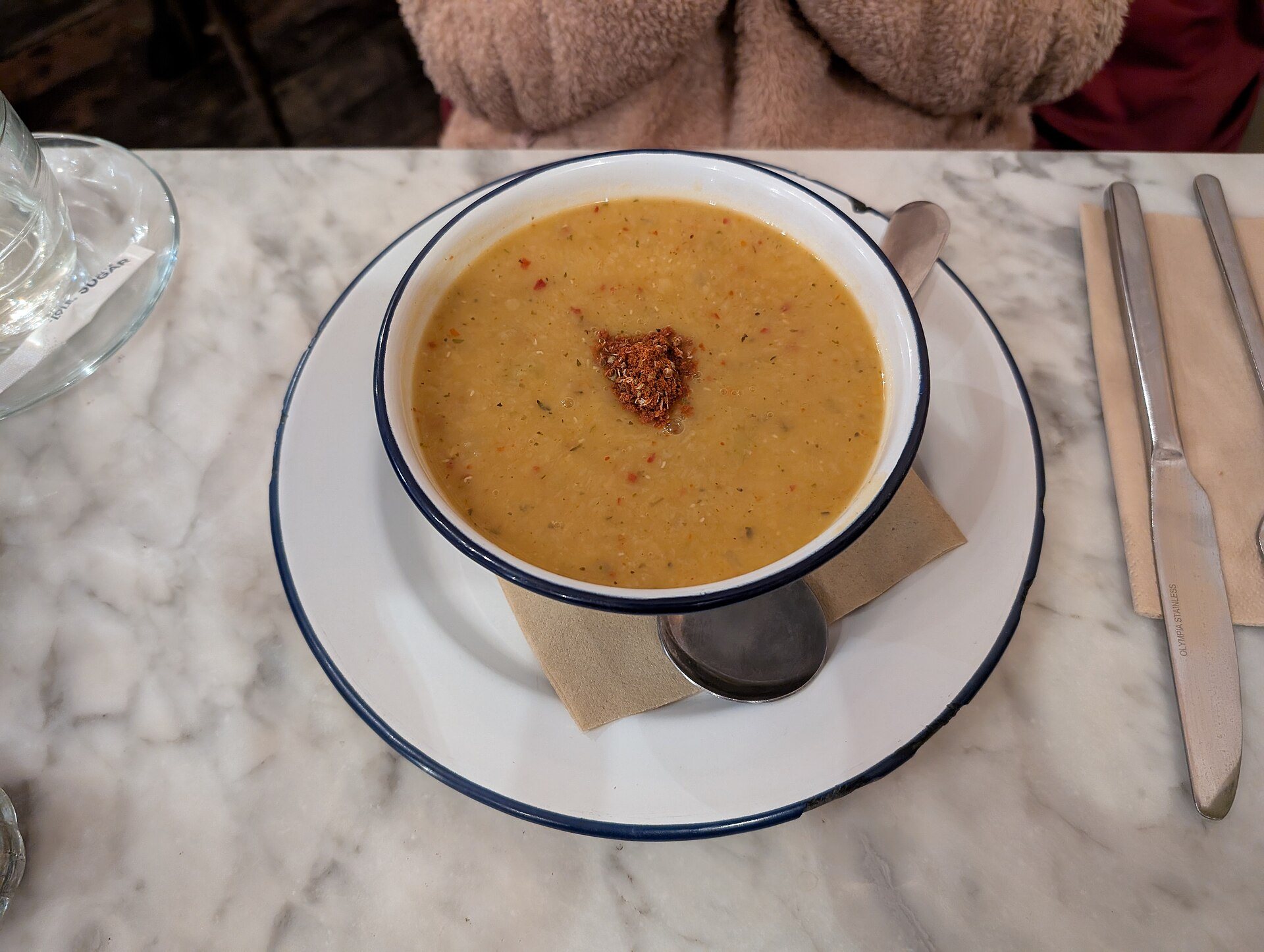 Red lentil soup in a white enamel bowl topped with chili flakes