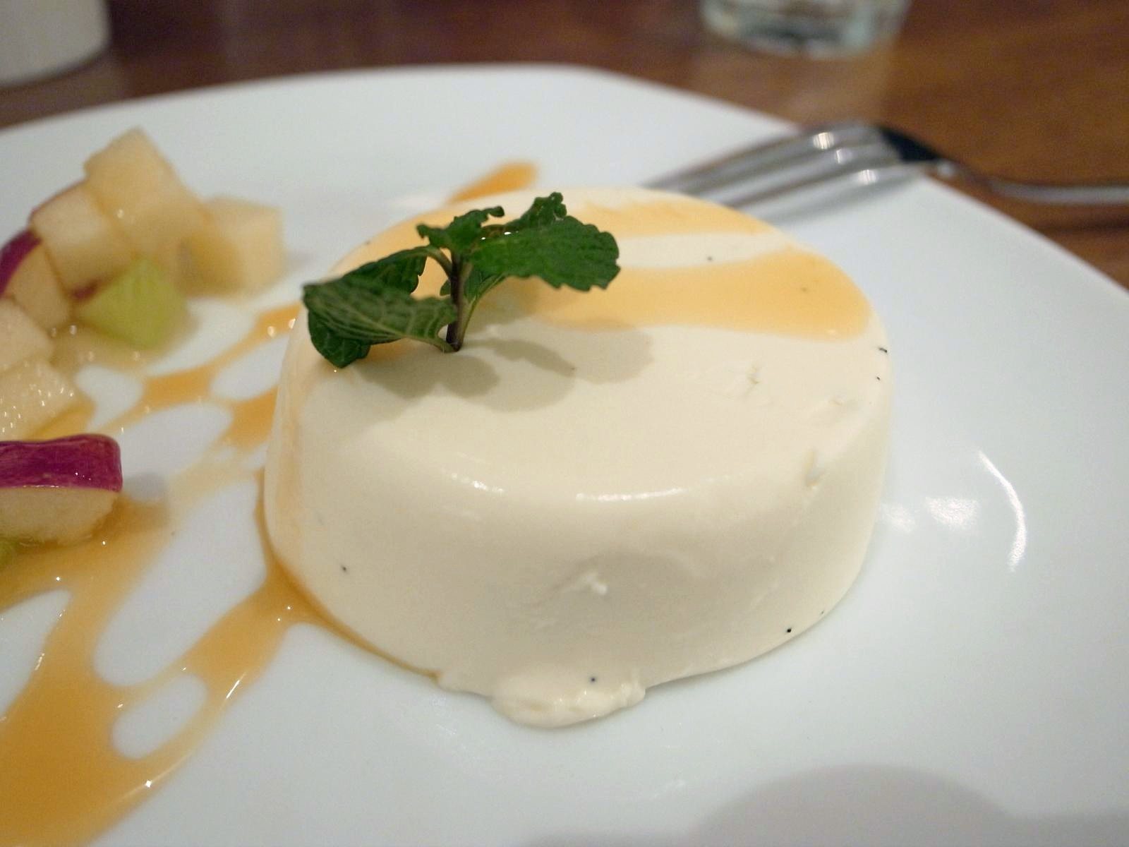 Vanilla panna cotta with a caramel drizzle, fresh fruit and mint