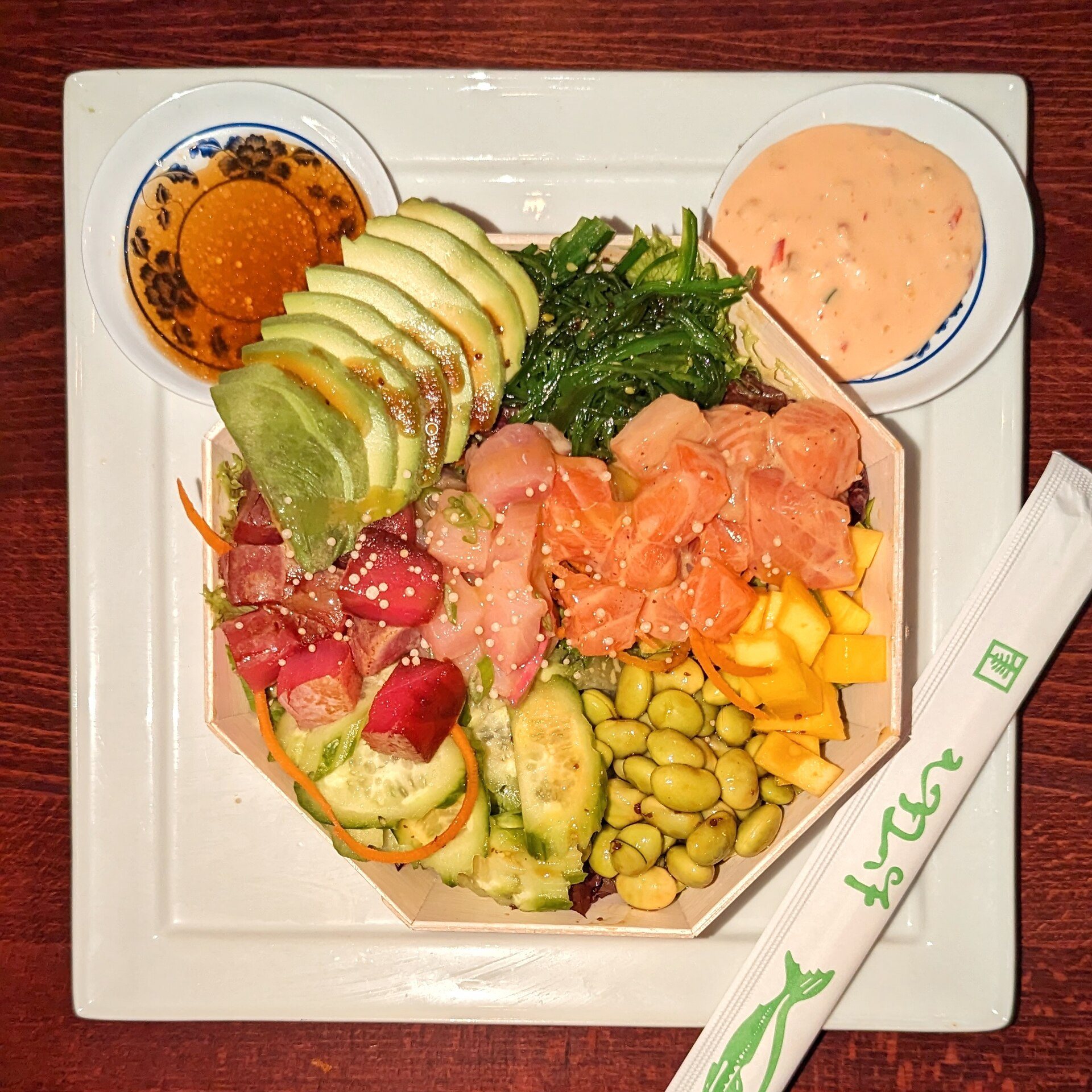 Salmon poke bowl with avocado, seaweed salad, edamame and pickled ginger