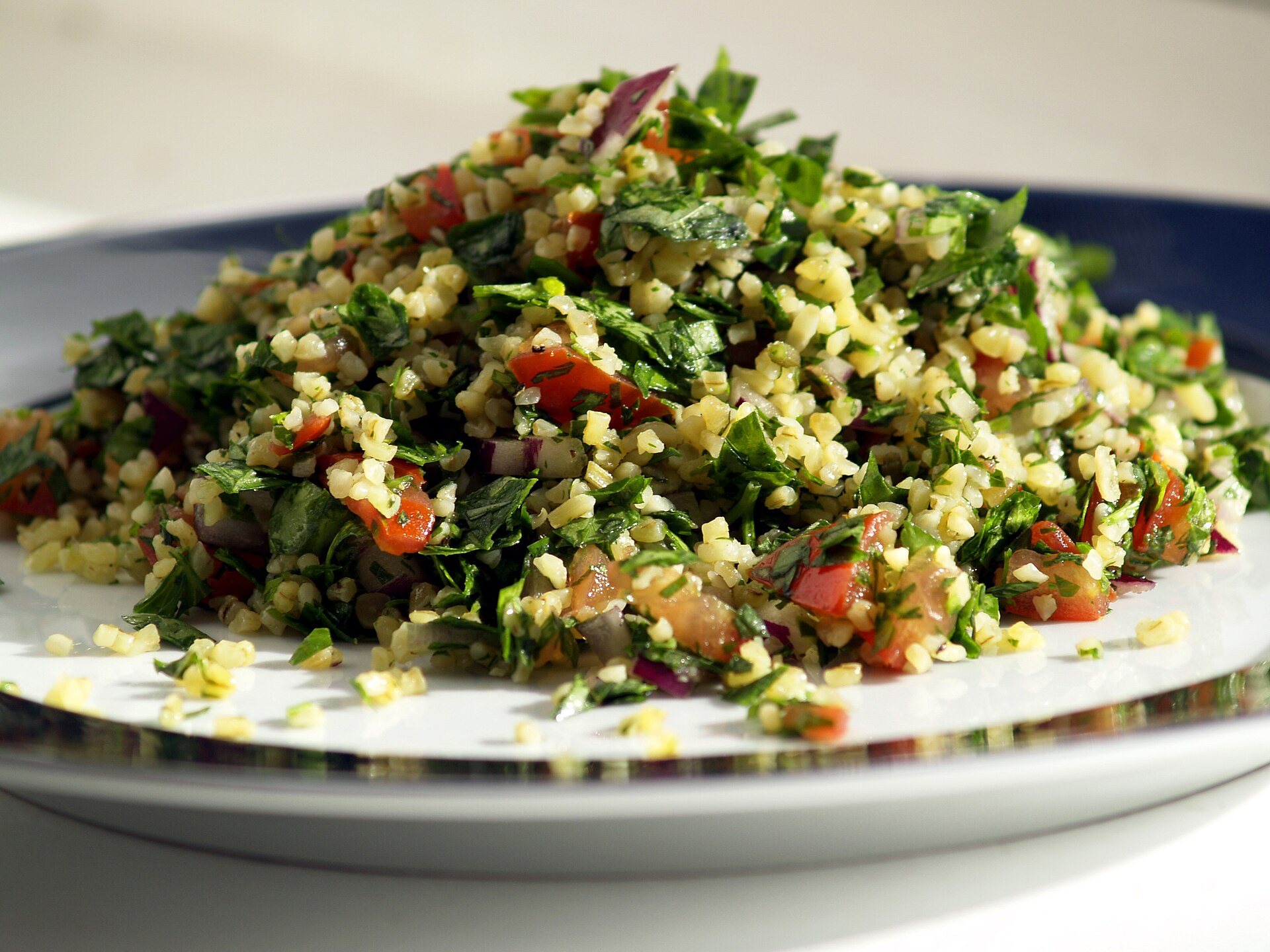 Tabbouleh salad with parsley, bulgur and tomatoes on a white plate